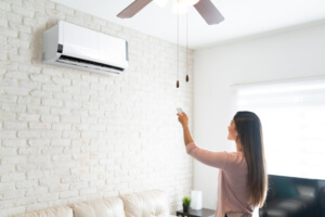 Photo d'une femme dans un salon en train d'allumer une climatisation fixée à un mur